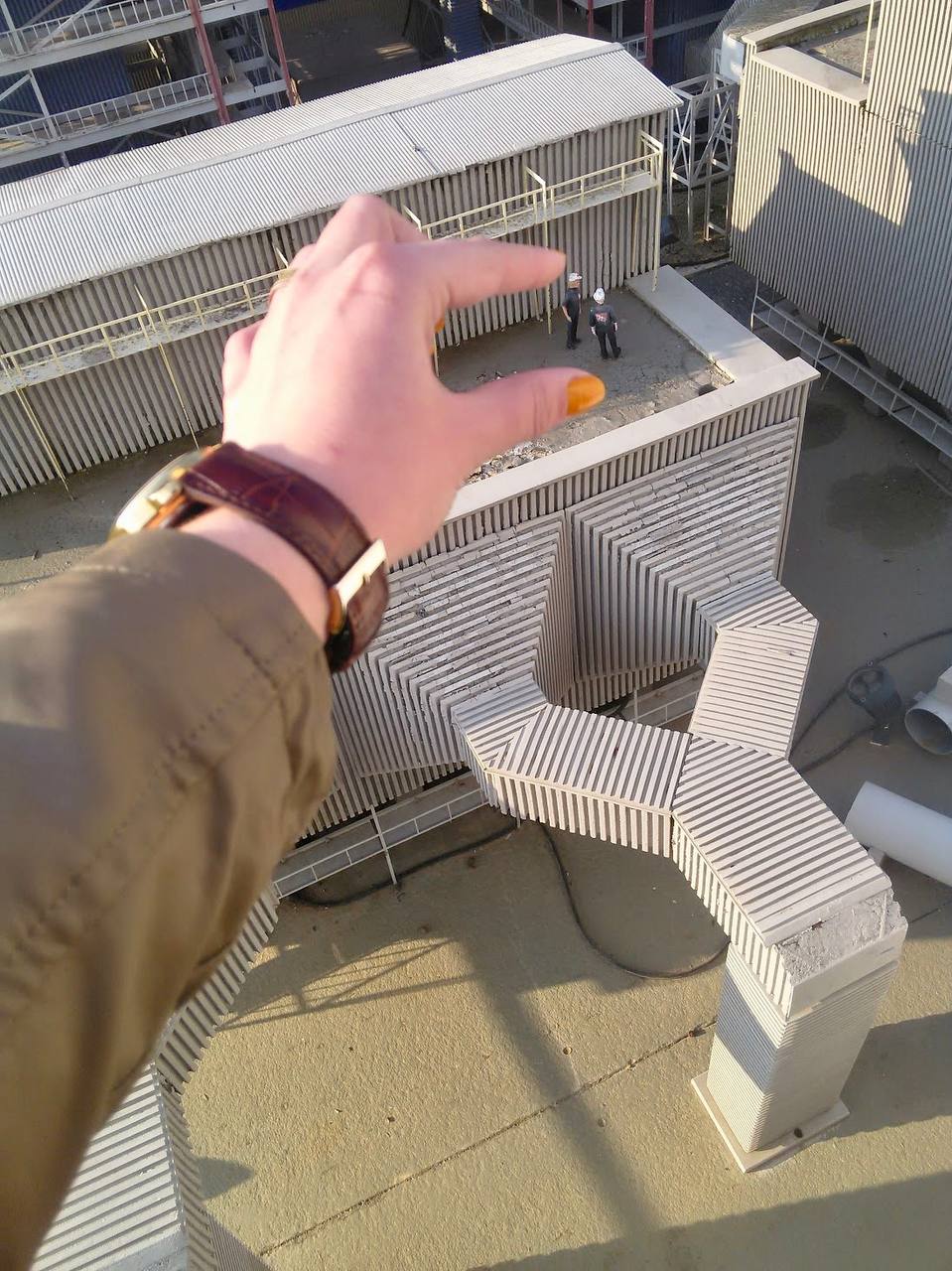 Рука указывает на конструкцию на крыше в солнечный день